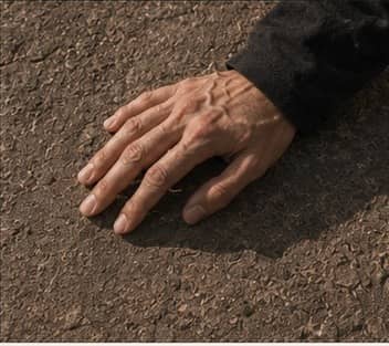 A hand resting on textured stone.